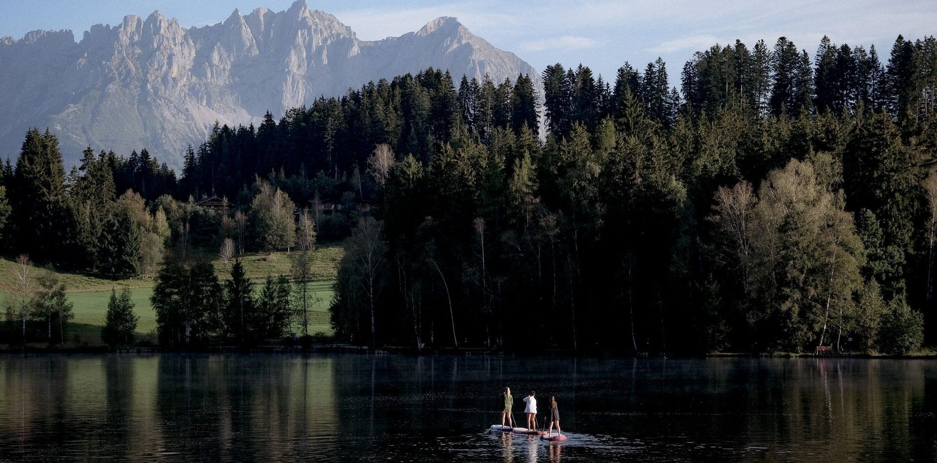 ein Berg Panorama Bild mit einem See und Standup Paddlern.